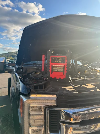 Portable jump-starter pack set in the engine bay of a pickup truck with its hood open